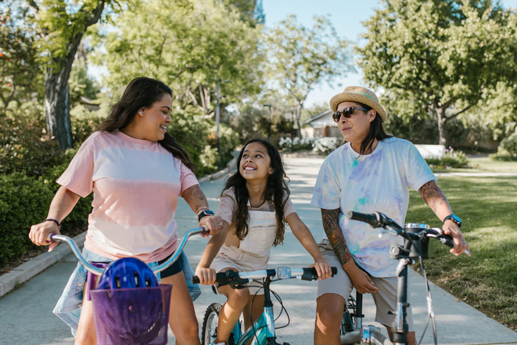 familia homosexual de mulleres cunha filla paseando xuntas en bicicleta