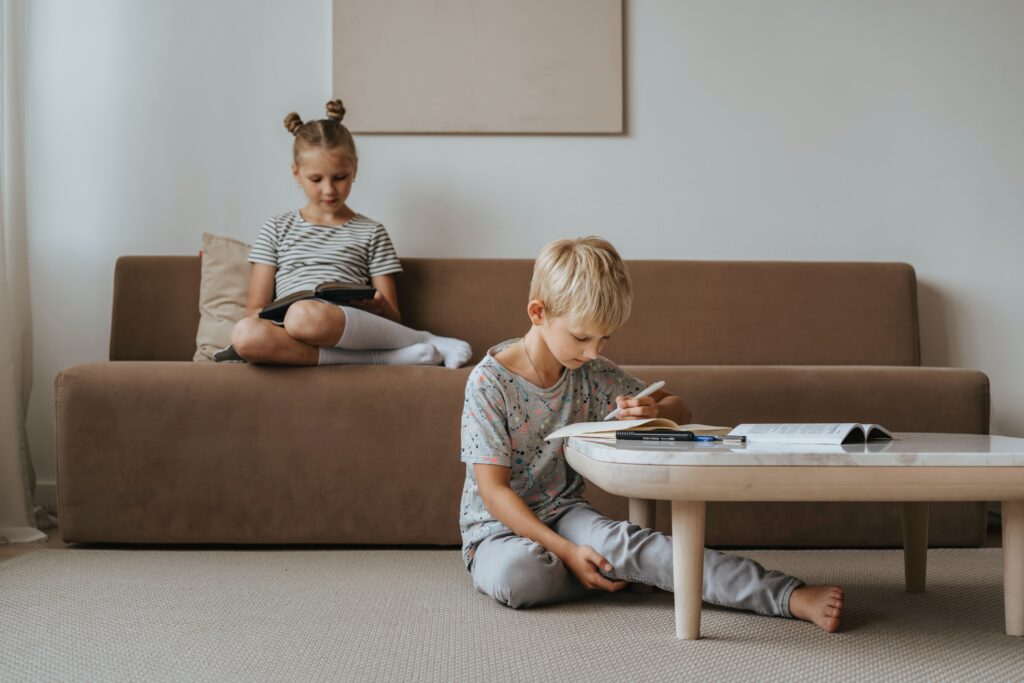 Unha nena e un neno adoptivos no salón da súa casa lendo e facendo os deberes
