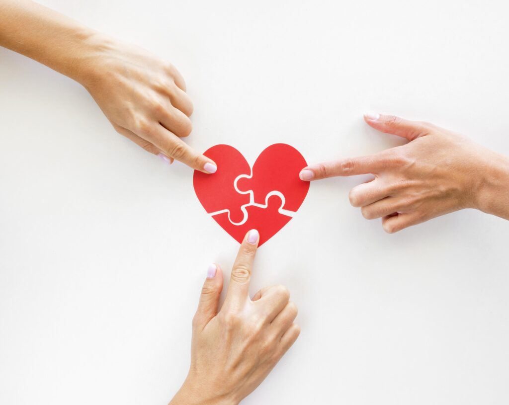 imagen de corazón en forma de puzzle, con 3 manos señalando