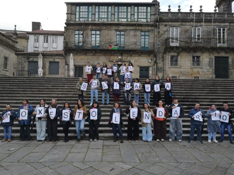 Persoas portan cartaces no acto de presentación x solidaria nas escaleiras da Praza da Quintana